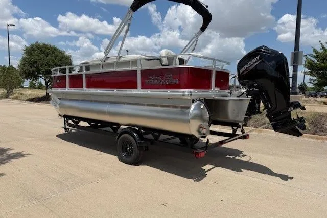 Slide: The Image of 2026 Sun Tracker Bass Buggy 18 DLX pontoon boat on trailer, parked outdoors. - 7