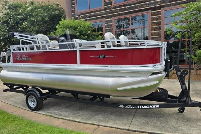 Slide: The Image of 2026 Sun Tracker Bass Buggy 18 DLX pontoon boat on trailer, parked outdoors. - 5