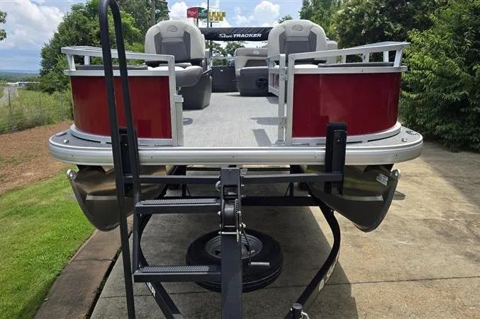 Slide: The Image of 2026 Sun Tracker Bass Buggy 18 DLX pontoon boat on trailer, parked outdoors. - 2