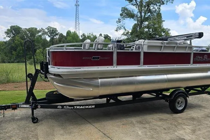 Slide: The Image of 2026 Sun Tracker Bass Buggy 18 DLX pontoon boat on trailer, parked outdoors. - 1