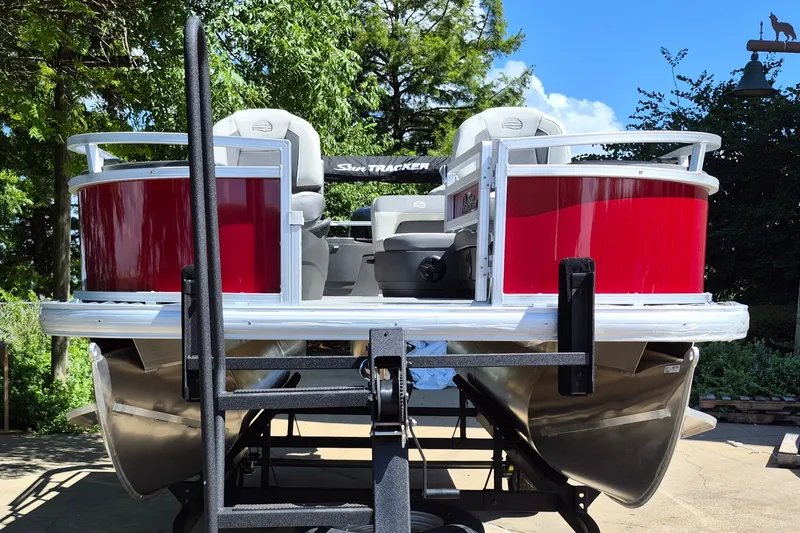 Slide: The Image of 2026 Sun Tracker Bass Buggy 18 DLX pontoon boat on trailer, vibrant red exterior. - 2