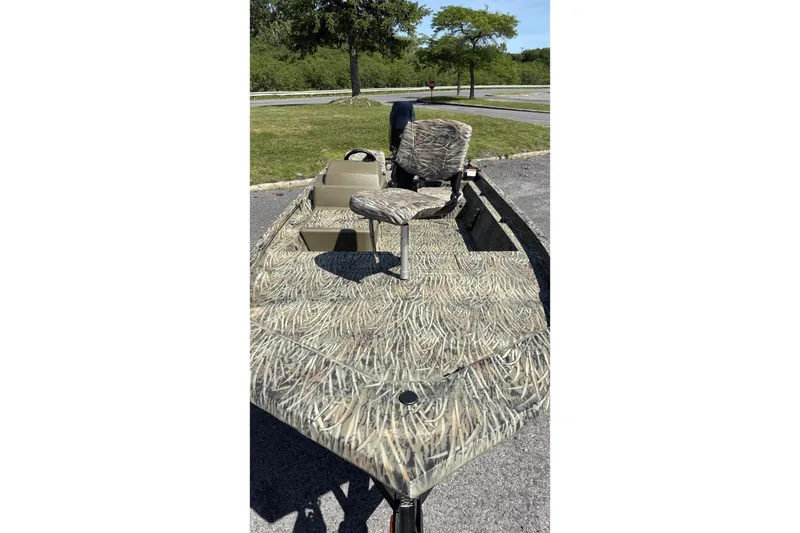 Slide: The Image of 2026 Tracker Grizzly 1754 SC boat with camouflage design, parked outdoors. - 2