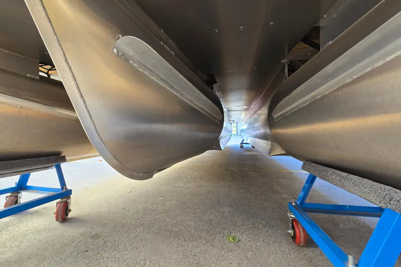 Slide: The Image of Underneath view of 2024 Godfrey Sweetwater 2486 SB pontoon boat on blue stands. - 17