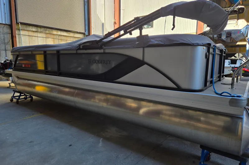 Slide: The Image of 2024 Godfrey Sweetwater 2486 SB pontoon boat in storage, covered and secured. - 2