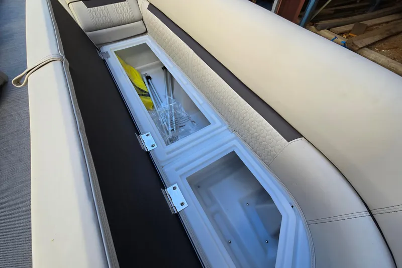 Slide: The Image of 2024 Godfrey Sweetwater 2486 SB boat seat storage compartment with open lid and visible contents. - 31