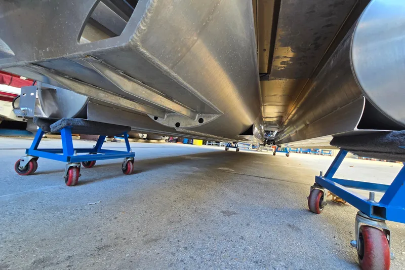 Slide: The Image of Underneath view of 2024 Godfrey Sweetwater 2486 SB pontoon boat on blue dollies. - 14