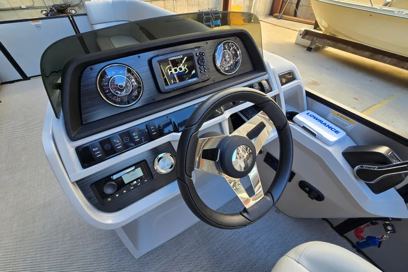 Slide: The Image of 2024 Godfrey Sweetwater 2486 SB boat dashboard with steering wheel and navigation controls. - 37