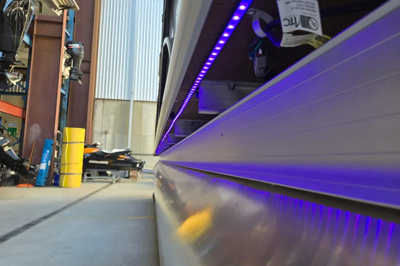 Slide: The Image of 2024 Godfrey Sweetwater 2486 SB pontoon with blue LED lights in a marina setting. - 46