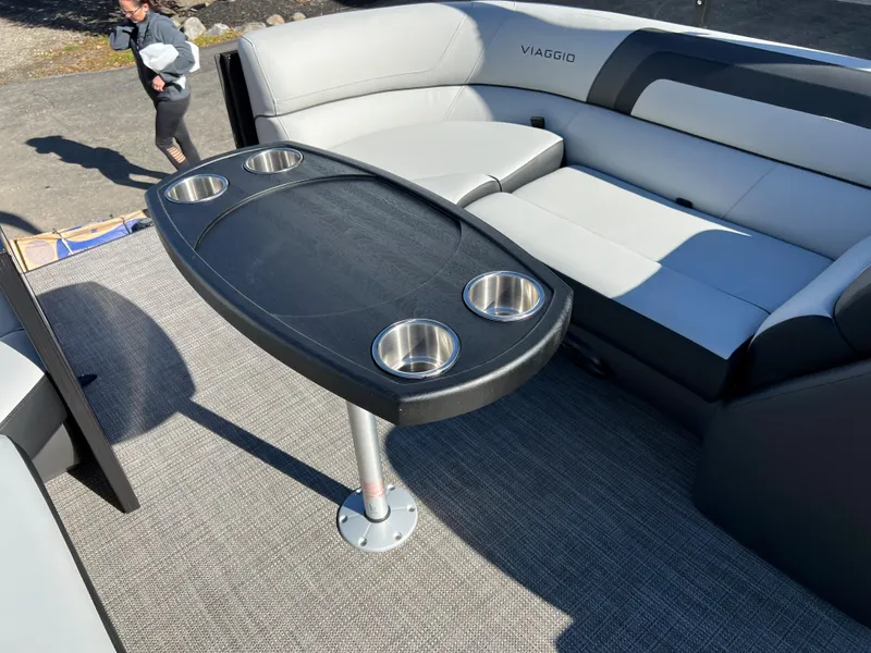 Slide: The Image of The image shows the interior of a Viaggio Lago 22U Tri Toon boat with a table and seating. - 23