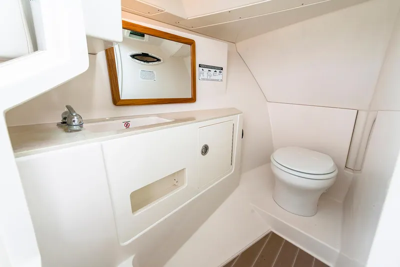 Slide: The Image of Manufacturer Provided Image: 2026 Sailfish 316 DC boat bathroom with sink, mirror, and toilet in white interior. - 10