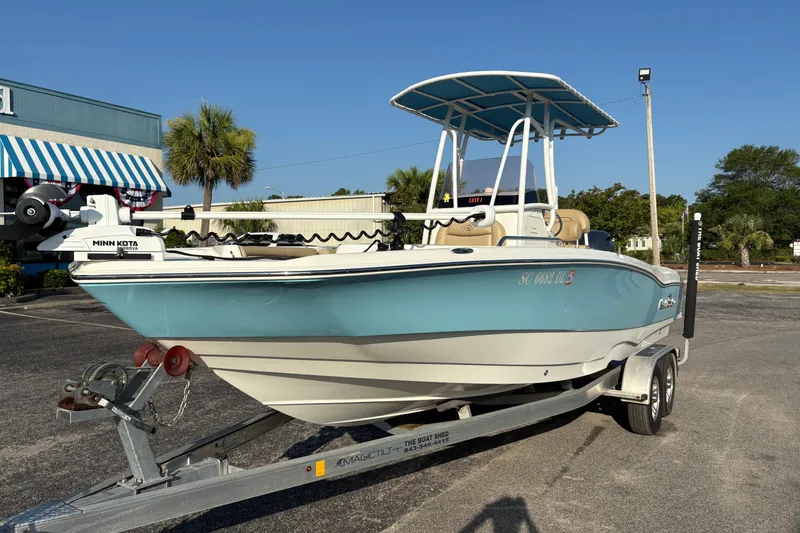 Slide: The Image of 2019 NauticStar 231 Hybrid boat on trailer, featuring a blue hull and T-top canopy. - 6