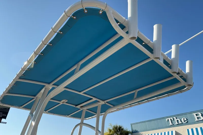 Slide: The Image of 2019 NauticStar 231 Hybrid boat canopy with rod holders against clear blue sky. - 18