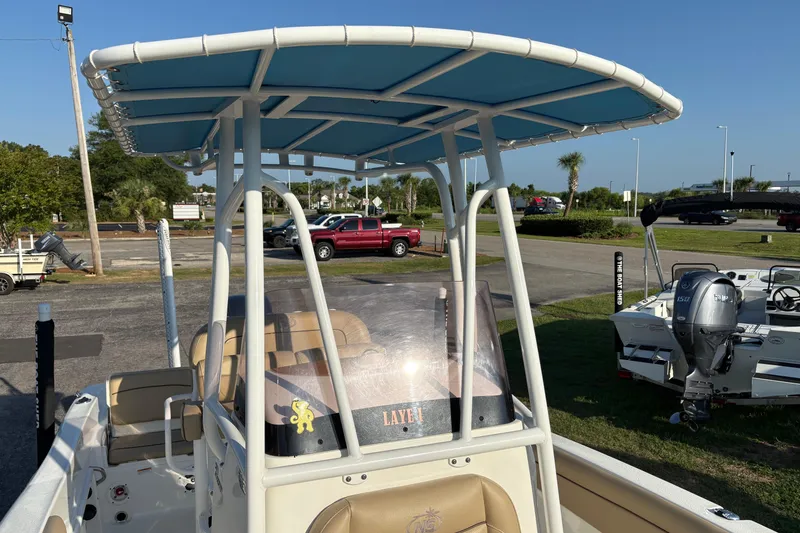 Slide: The Image of 2019 NauticStar 231 Hybrid boat with blue canopy, parked outdoors. - 22