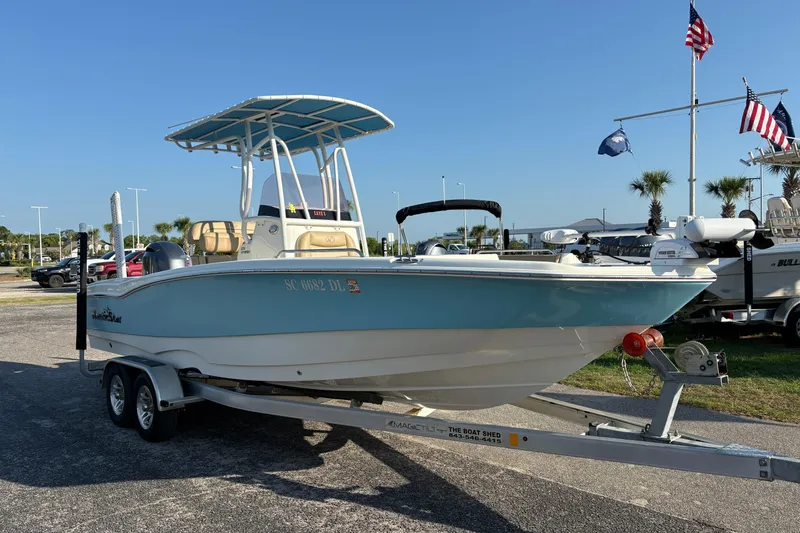 Slide: The Image of 2019 NauticStar 231 Hybrid boat on trailer, displayed outdoors with flags in the background. - 4