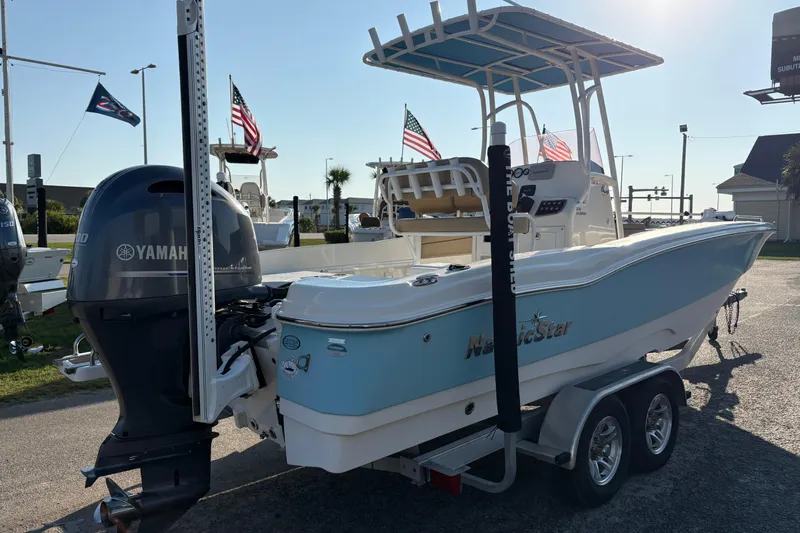 Slide: The Image of 2019 NauticStar 231 Hybrid boat with Yamaha engine on trailer, flags in background. - 2