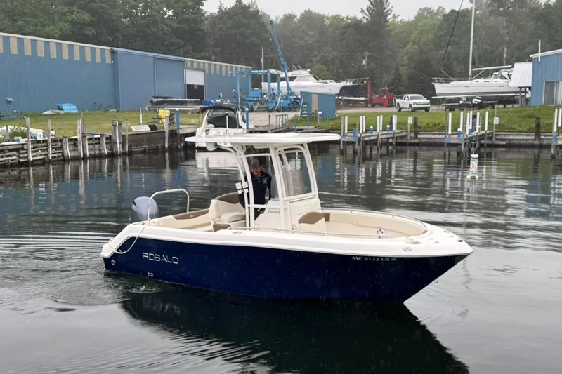 Slide: The Image of 2017 Robalo R222 Center Console boat docked in a marina, surrounded by calm water. - 2