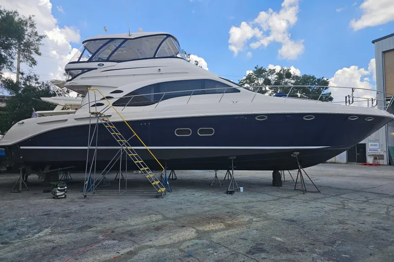 Slide: The Image of 2006 Sea Ray 580 Sedan Bridge yacht on dry dock under a clear blue sky. - 44