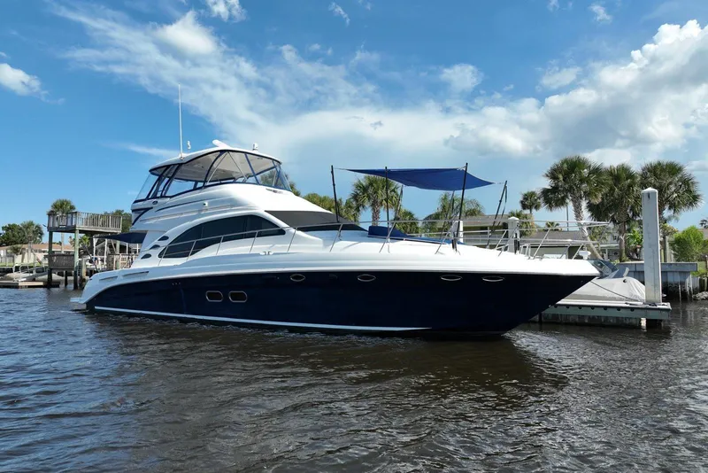 Slide: The Image of 2006 Sea Ray 580 Sedan Bridge yacht docked on a sunny day with palm trees. - 6
