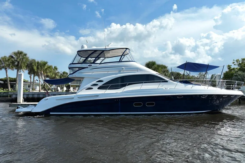 The Image of 2006 Sea Ray 580 Sedan Bridge yacht docked on a sunny day with palm trees. - 0
