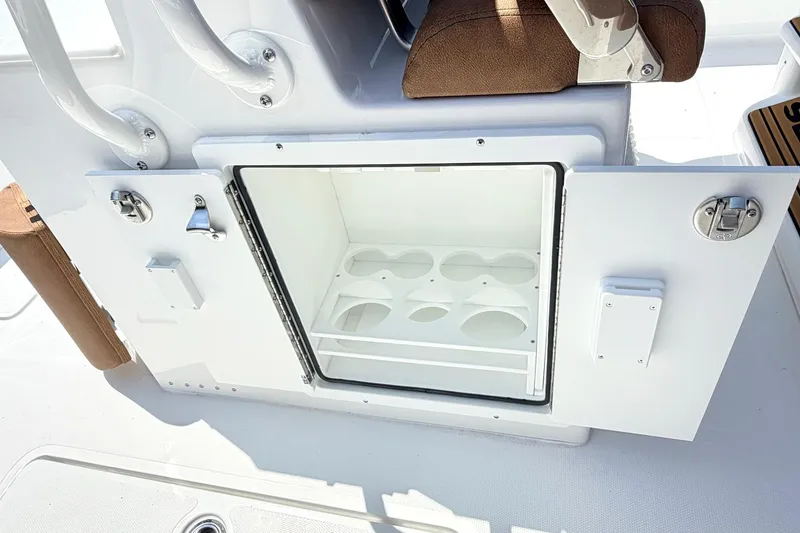 Slide: The Image of 2027 Sea Hunt Ultra 275 SE boat storage compartment with open door and cup holders. - 8