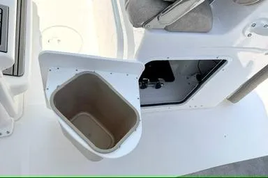 Slide: The Image of 2027 Sea Hunt Ultra 245 SE boat interior with open storage compartment and trash bin. - 17