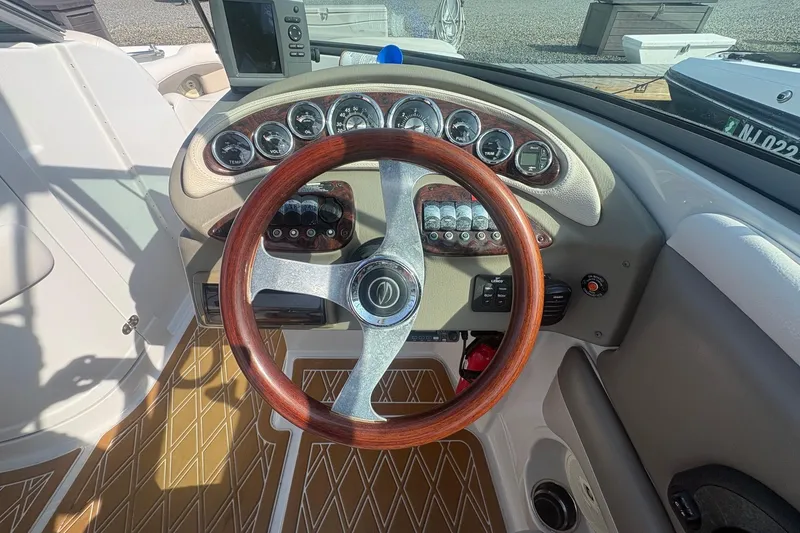 Slide: The Image of Steering wheel and dashboard of 2013 Crownline Eclipse E6 boat, featuring wood accents and gauges. - 6
