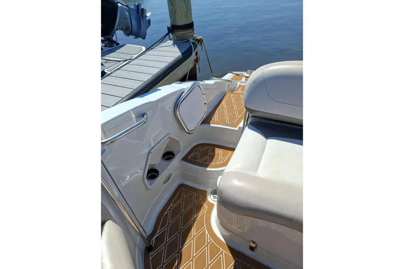 Slide: The Image of 2013 Crownline Eclipse E6 boat interior with cushioned seating and stylish flooring near a dock. - 5