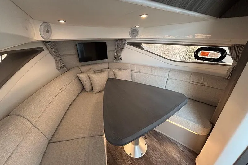 Slide: The Image of 2024 Sea Ray Sundancer 320 Outboard cabin interior with seating, table, and TV. - 33