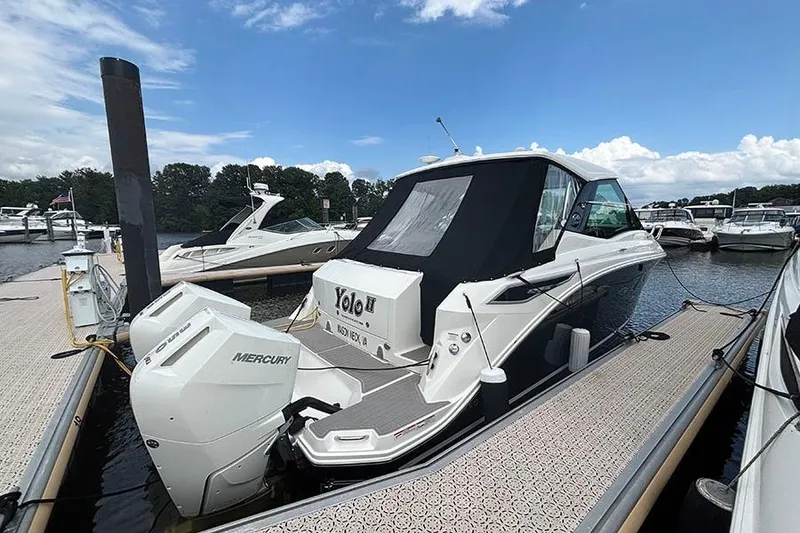 Slide: The Image of 2024 Sea Ray Sundancer 320 Outboard docked, featuring dual Mercury engines, under a clear blue sky. - 18