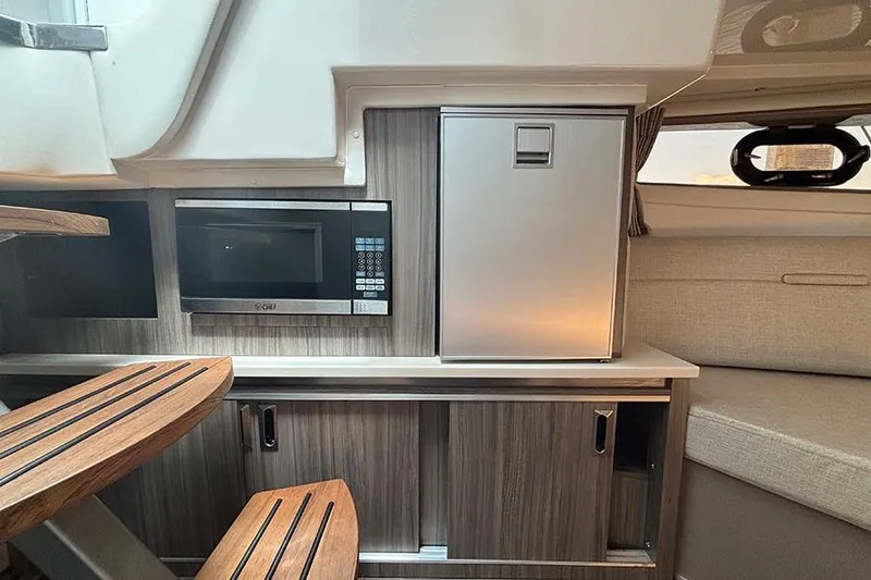 Slide: The Image of 2024 Sea Ray Sundancer 320 Outboard interior with microwave and compact fridge. - 35