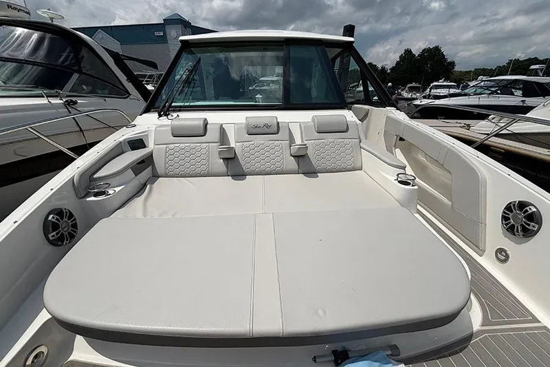 Slide: The Image of 2024 Sea Ray Sundancer 320 Outboard boat interior with cushioned seating and cup holders. - 40