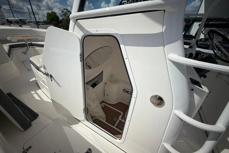 Slide: The Image of 2022 Edgewater 340CC boat interior with open cabin door, showcasing sleek design and wood flooring. - 36