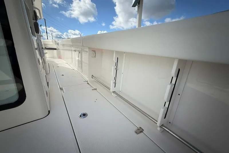 Slide: The Image of 2022 Edgewater 340CC boat deck with storage compartments under a blue sky. - 23
