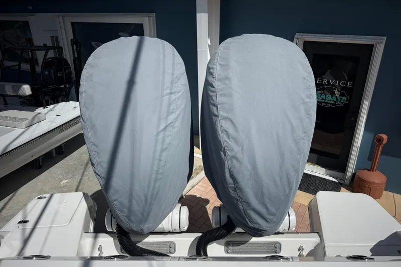 Slide: The Image of Covered outboard motors on a 2022 Edgewater 340CC boat, parked near a service entrance. - 6