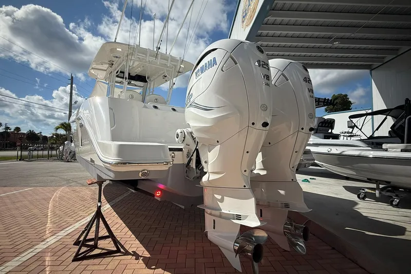 Slide: The Image of 2022 Edgewater 340CC boat with twin Yamaha 425 engines, parked outdoors under a clear sky. - 3