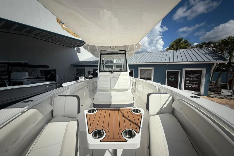Slide: The Image of 2022 Edgewater 340CC boat interior with seating and table, displayed outdoors. - 45