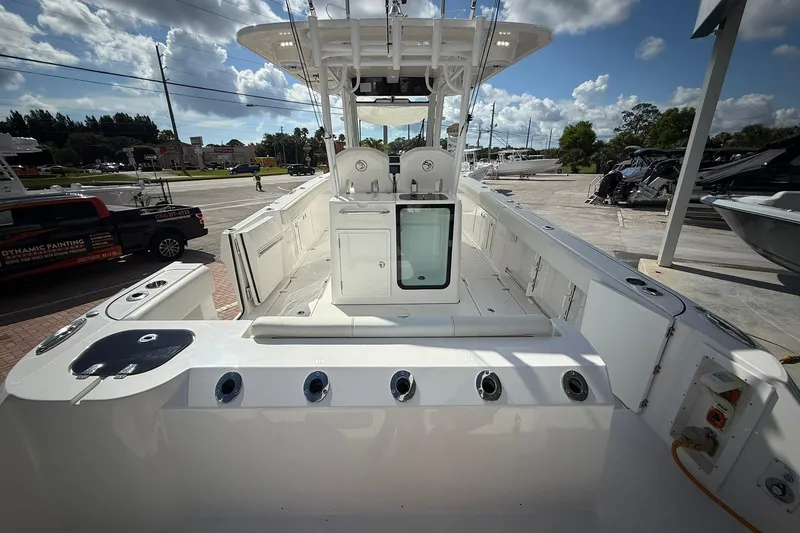 Slide: The Image of 2022 Edgewater 340CC boat interior with seating and storage, under a partly cloudy sky. - 7