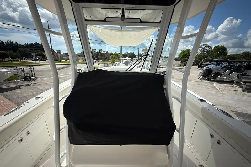 Slide: The Image of 2022 Edgewater 340CC boat interior with covered console, parked outdoors under a cloudy sky. - 27