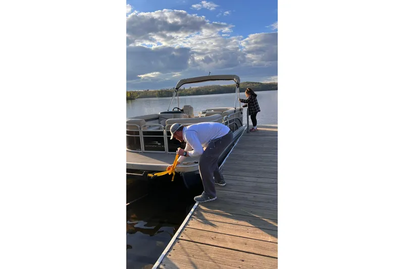 Slide: The Image of Man securing 2016 Bennington SX 20 pontoon boat at dock, scenic lake view. - 4