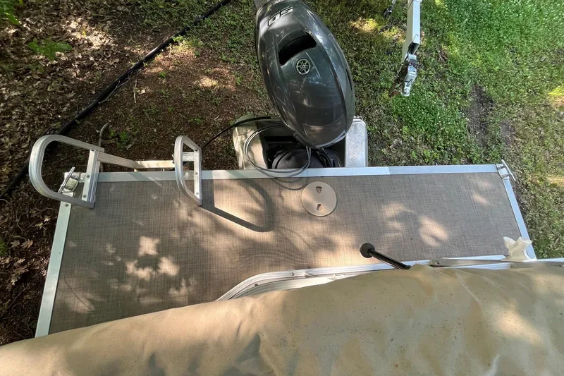 Slide: The Image of 2016 Bennington SX 20 boat deck with motor and ladder, surrounded by grass and trees. - 8