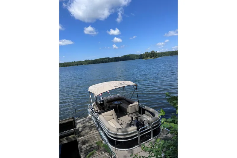 The Image of 2016 Bennington SX 20 pontoon boat docked on a serene lake under a clear blue sky. - 1