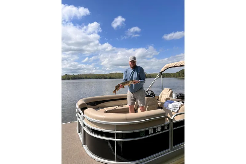 Slide: The Image of Man holding fish on 2016 Bennington SX 20 pontoon boat, scenic lake view. - 5