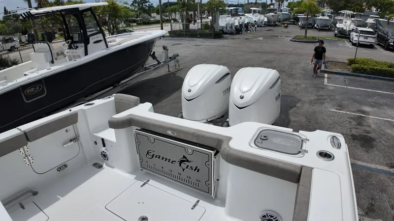 Slide: The Image of The image shows a Sea Hunt Gamefish 30 boat with two engines in a parking lot. - 10