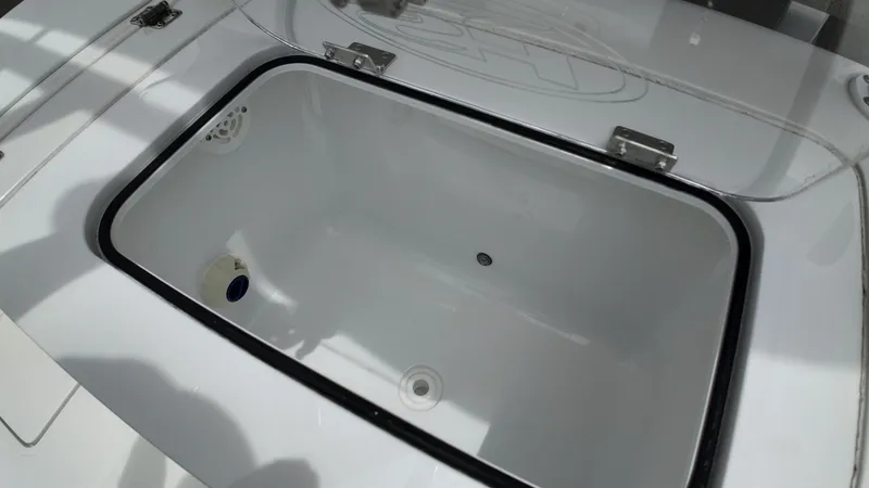Slide: The Image of An open storage compartment on a boat with a transparent lid and a drain opening. - 44
