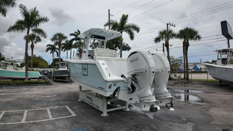 Slide: The Image of 2027 Sea Hunt Ultra 265 SE on a parking lot with palm trees in the background. - 2