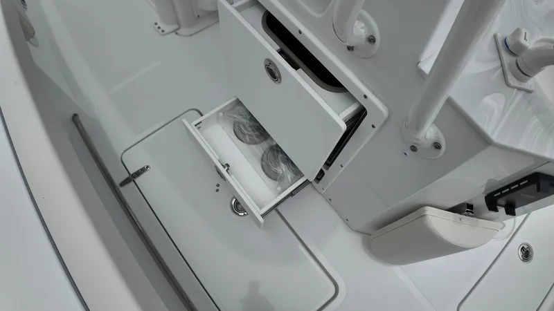Slide: The Image of An open storage compartment on a Sea Hunt Ultra 265 SE boat, revealing two cup holders. - 20