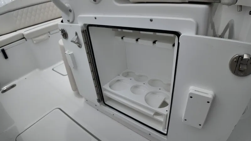 Slide: The Image of An open storage compartment on a boat with cup holders and cushioned seating in the background. - 50