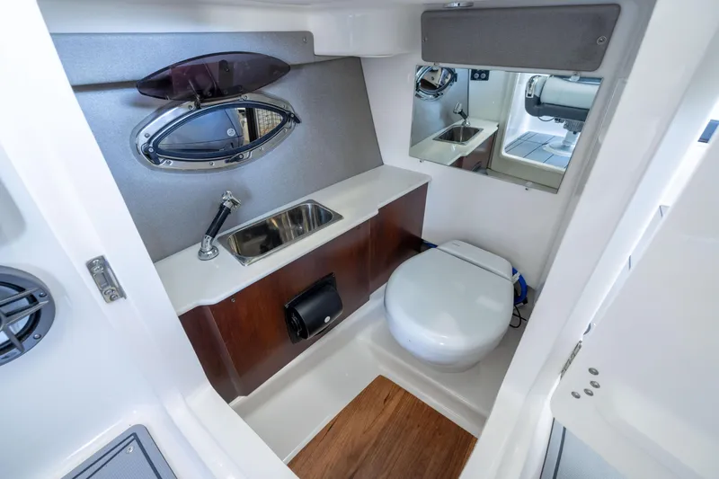Slide: The Image of 2026 Chaparral 250 OSX boat bathroom with sink, toilet, and mirror. - 16