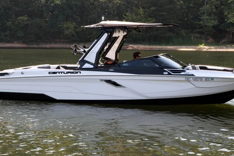 Slide: The Image of 2022 Centurion Ri265 boat cruising on a calm lake with lush forest background. - 4