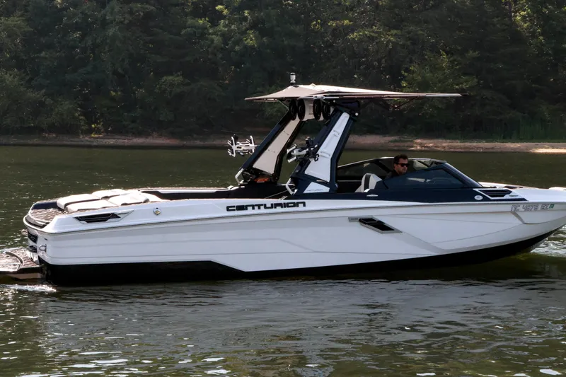 Slide: The Image of 2022 Centurion Ri265 boat cruising on a calm lake with lush forest backdrop. - 6